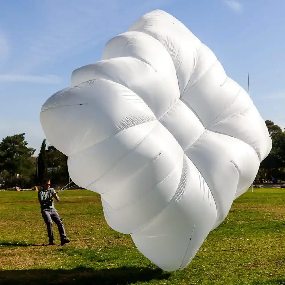 Inflated white rectangular canopy on the ground, held by a person on a lawn