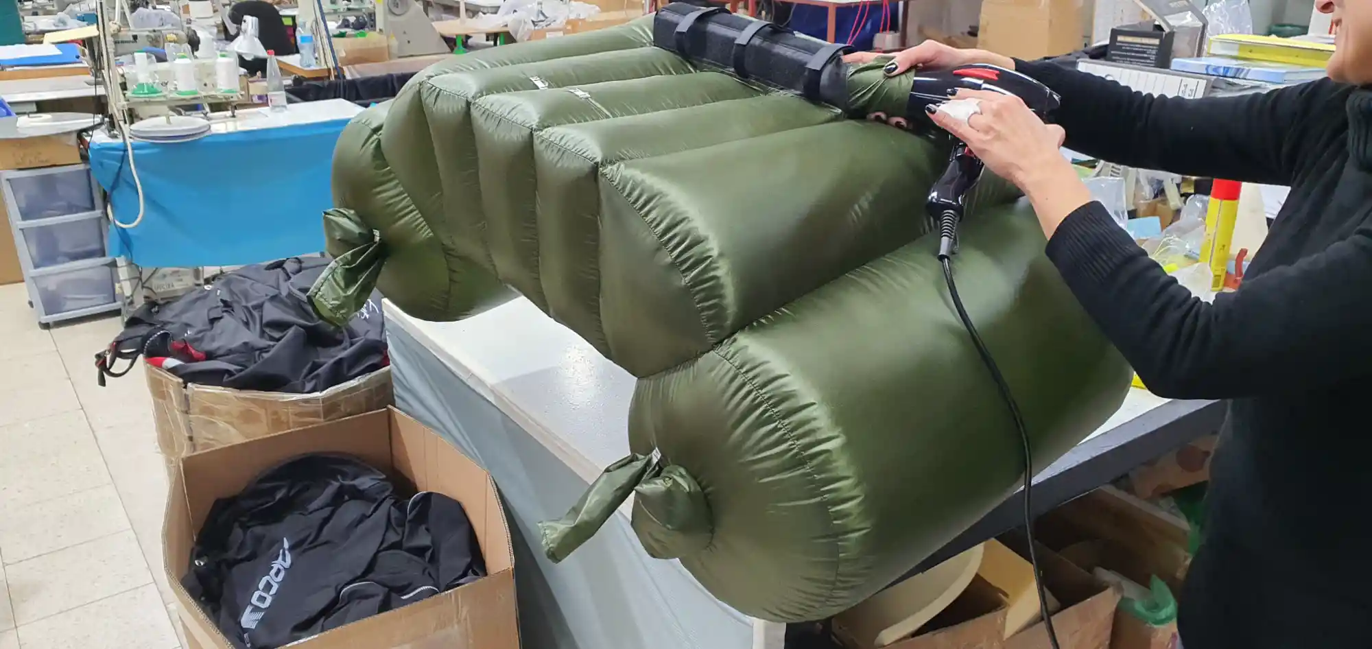 Multi-chamber olive green airbag being inflated with a fan in a workshop