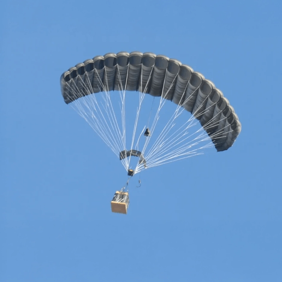 Single ram-air parachute carrying a suspended cargo load in flight against a blue sky