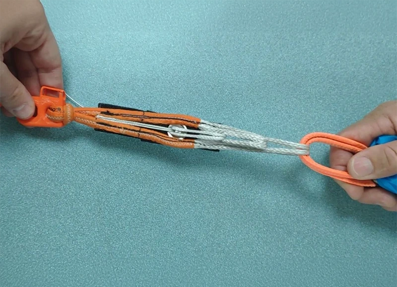 3-ring release with an orange loop and Dyneema lines, held in two hands