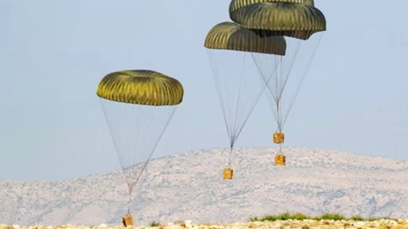 Several loads under round canopies during an airdrop over dry hills
