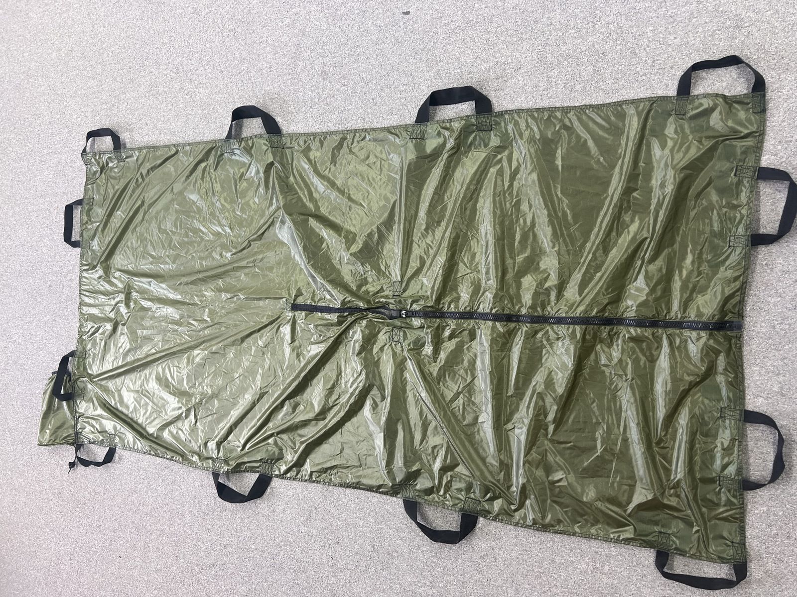 Olive green extraction stretcher laid flat, with a central zipper and webbing handles