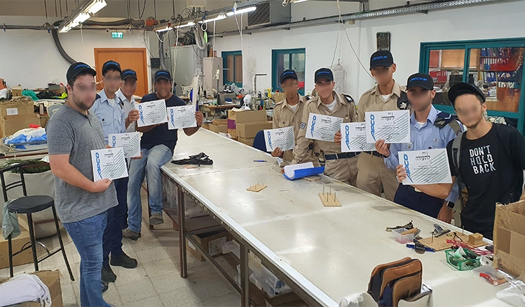 Packing training course for air force personnel: participants holding certificates in the workshop, faces blurred