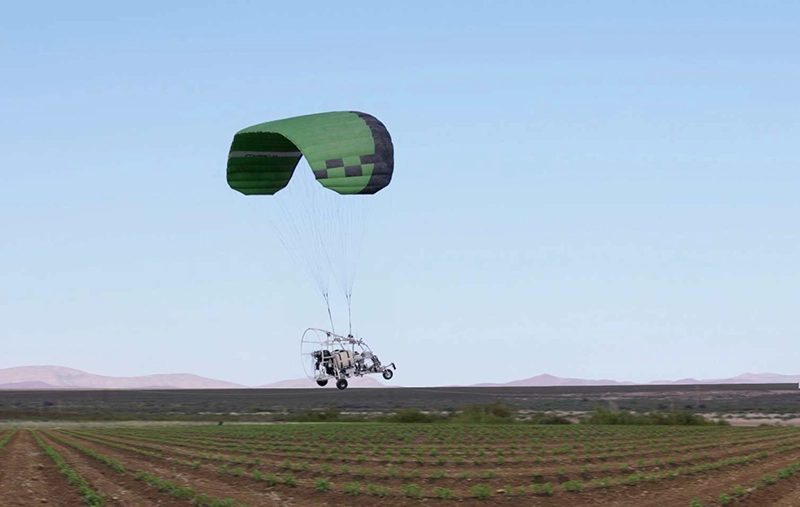 Motorschirm mit grüner Kappe fliegt über ein bestelltes Feld