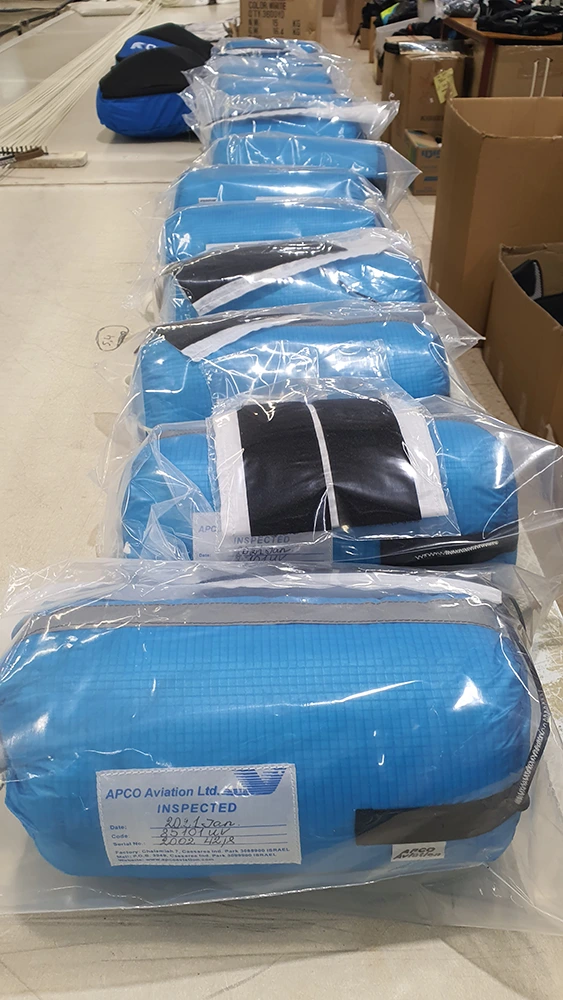 Packed blue parachutes in protective film, each with an “Inspected” label showing date, code and serial number