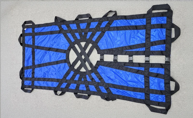 Textile stretcher laid flat: blue fabric with black webbing, carry handles and buckles