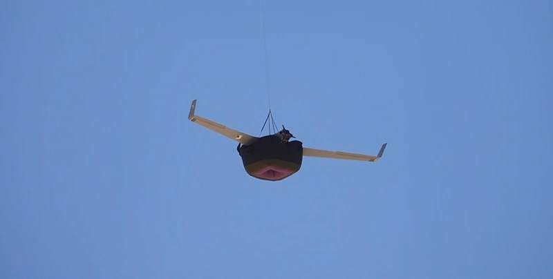 Fixed-wing UAV under a parachute with an inflated airbag below the fuselage