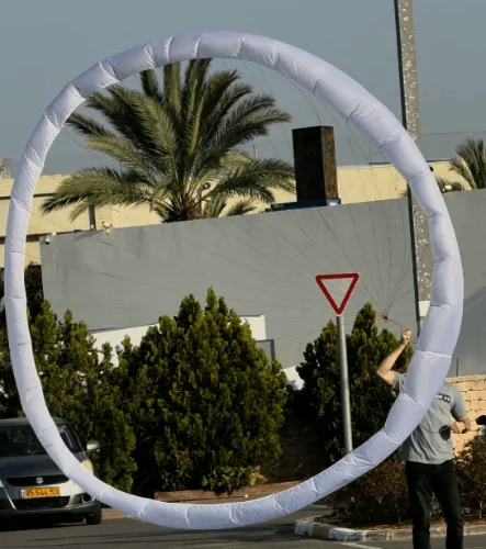 Deployed annular canopy forming a large textile ring in front of palm trees and buildings
