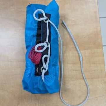 Packed annular parachute in a blue deployment bag with a line on a table