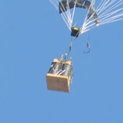 Load with a crash pad on its underside descending under a parachute