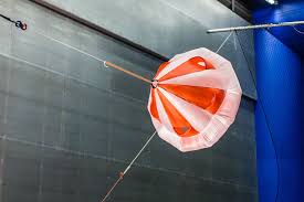 Red and white decelerator canopy on a tether line during a wind tunnel test
